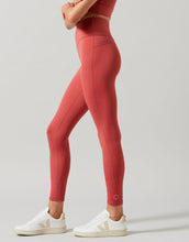 Person wearing red leggings and white sneakers on a light gray background