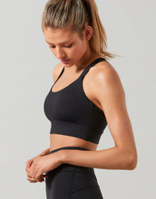 Woman wearing a black sports bra against a plain background