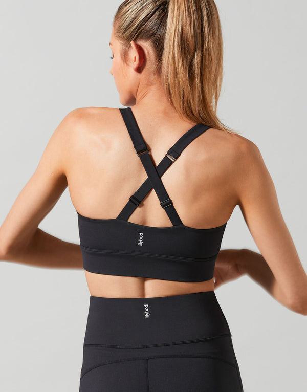 Woman wearing a black sports bra and leggings on a light gray background