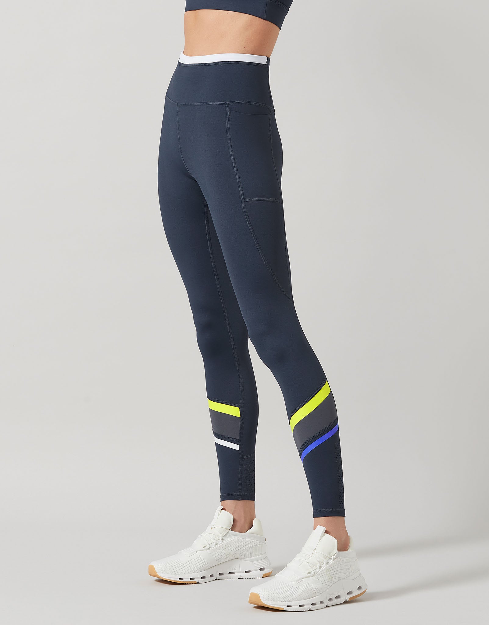 Navy leggings with colorful stripes worn by a person on a gray background