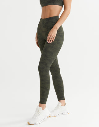 Person wearing green leggings and white sneakers on a white background
