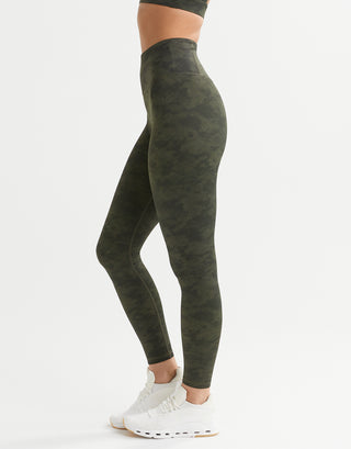 A woman wearing green camo leggings and white runners.