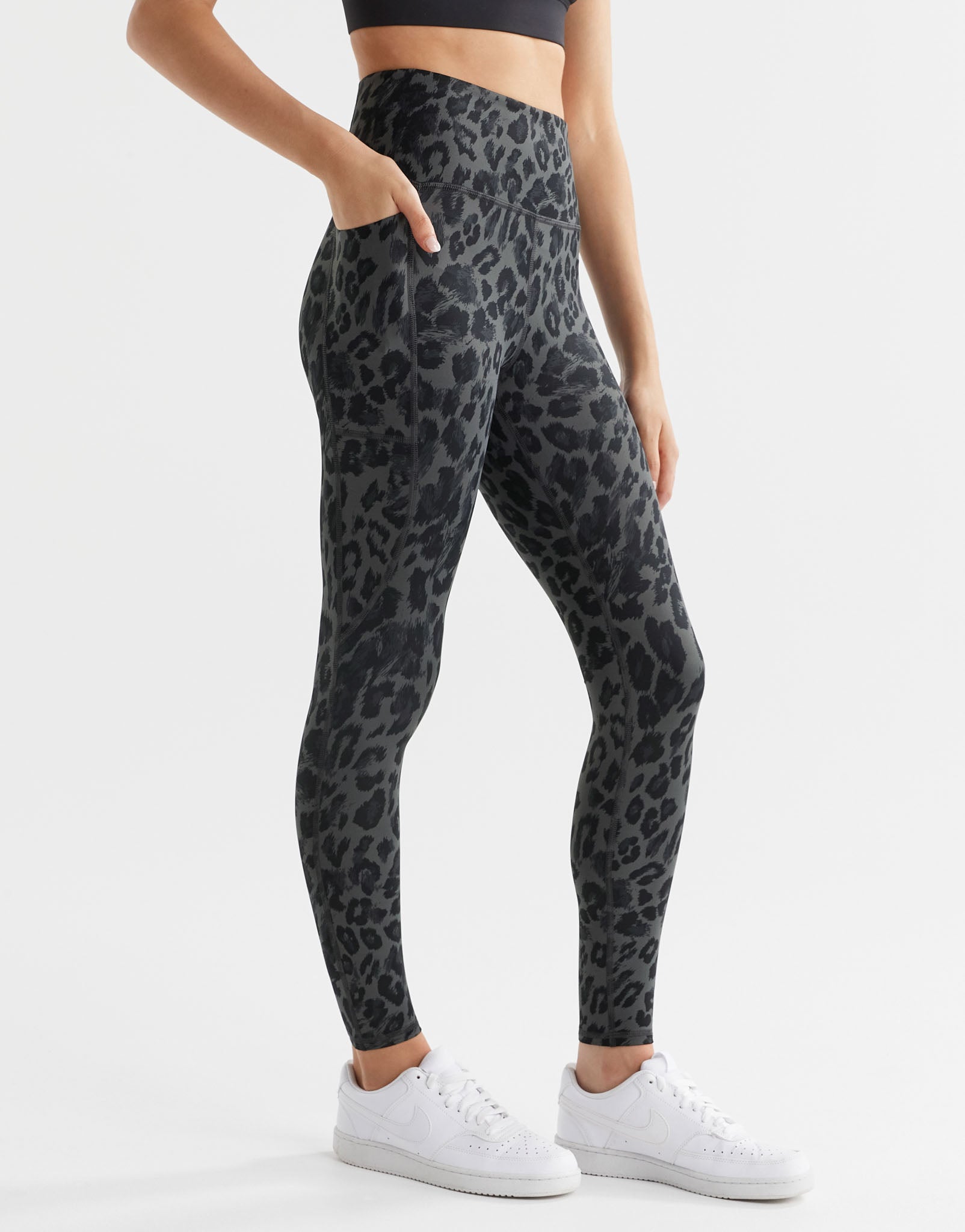A woman wearing grey leopard print leggings with pockets.