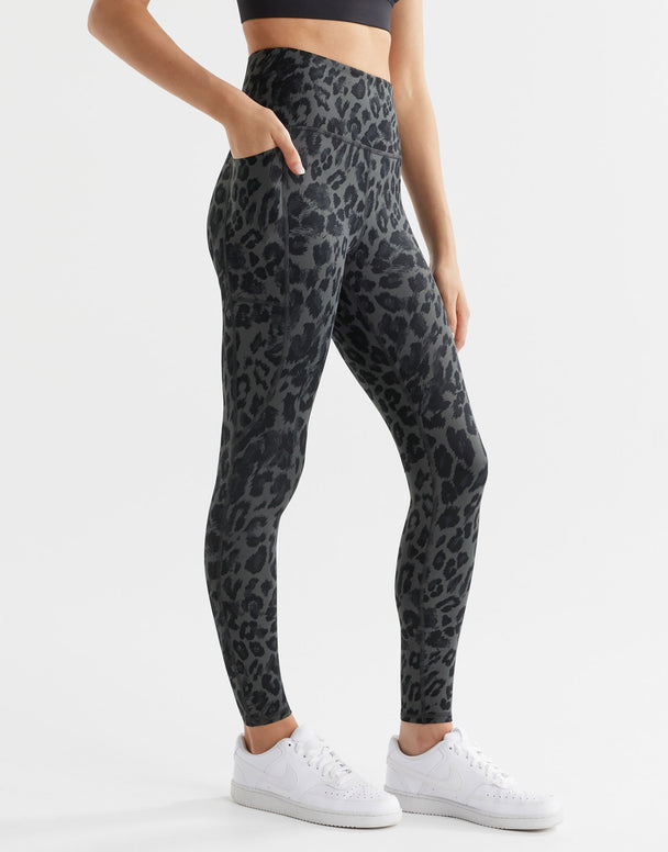 A woman wearing grey leopard print leggings with pockets.