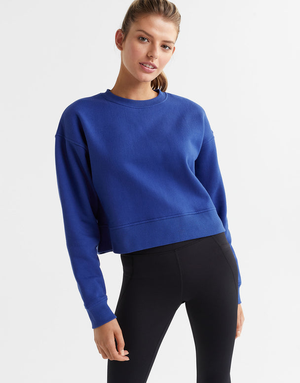 Woman wearing a blue sweatshirt and black leggings on a white background