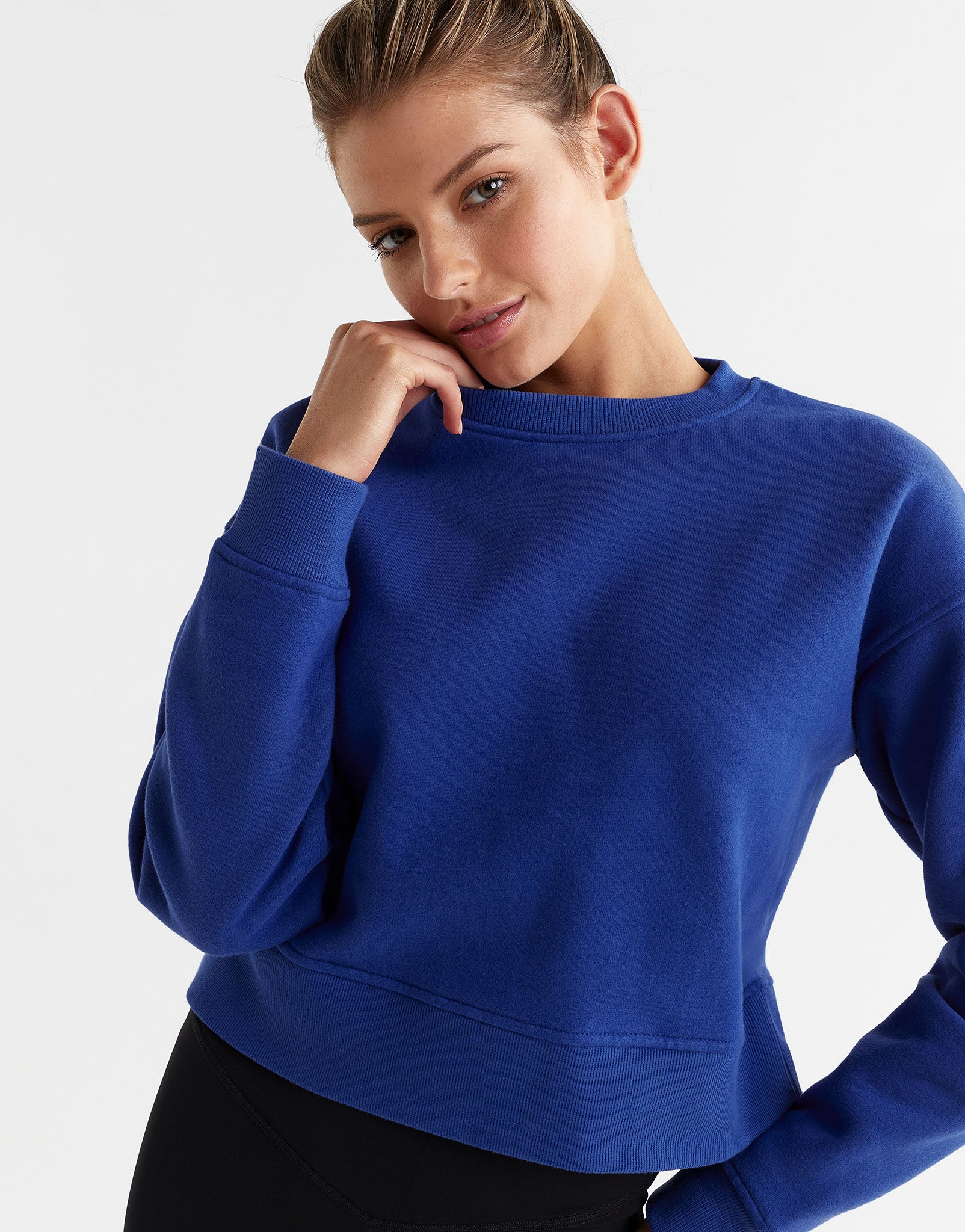 Woman wearing a blue sweatshirt on a light gray background