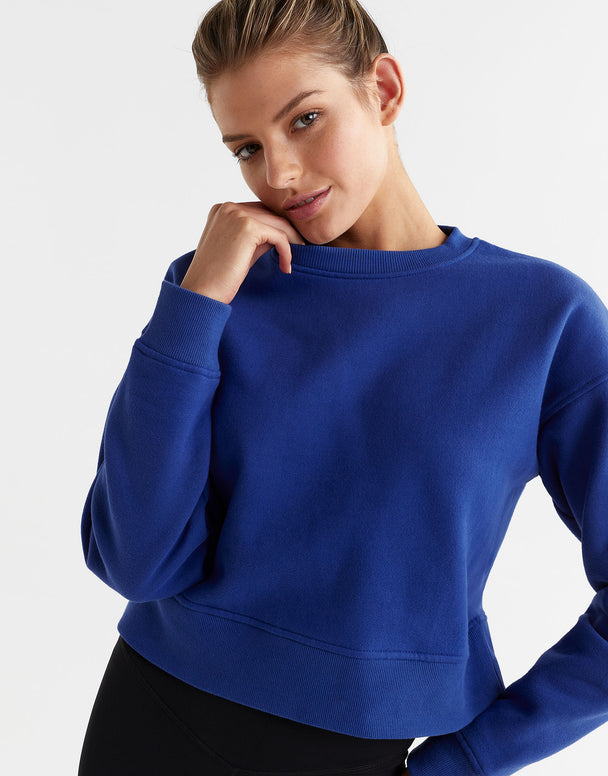 Woman wearing a blue sweatshirt on a light gray background