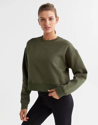 A woman wearing an olive green sweater and black leggings.