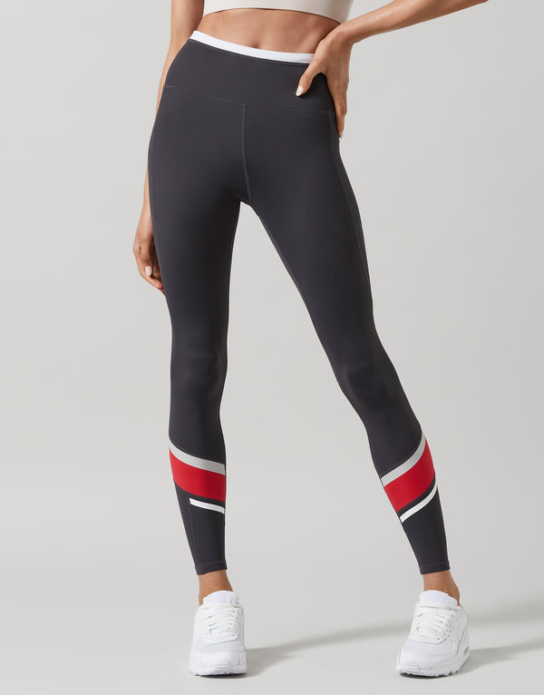Black leggings with red and white stripes on a gray background