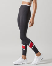 Black leggings with red and white stripes worn by a person on a gray background