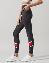 Black leggings with red and white stripes worn by a person on a gray background