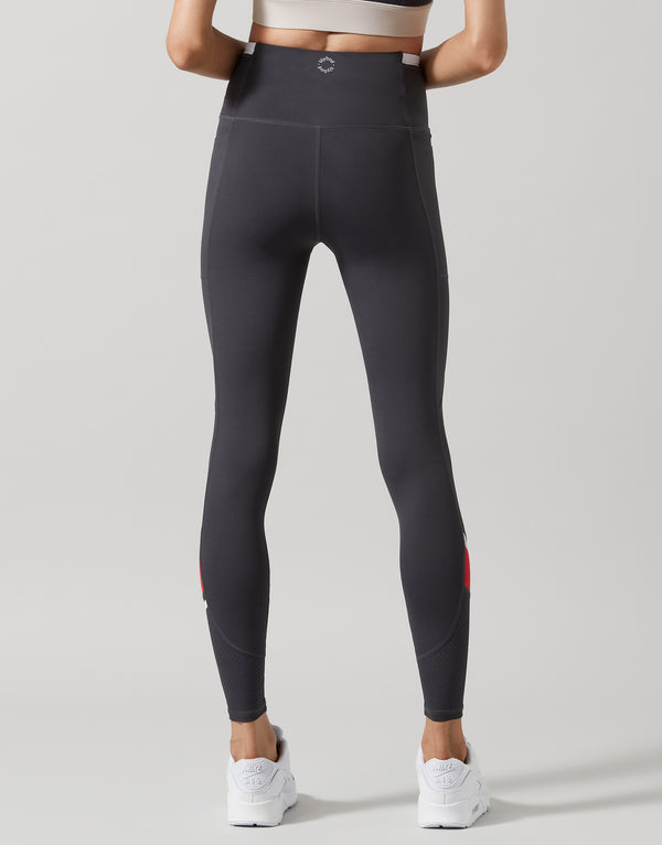 Person wearing black leggings with red accents on a white background