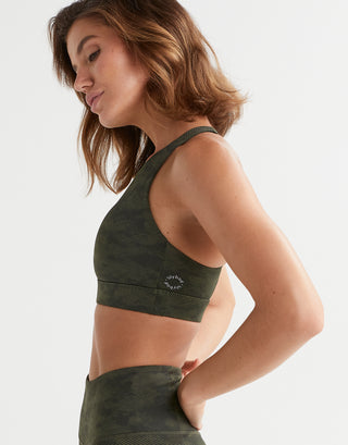 A model wearing a green camo Lilybod sports bra and legggings.