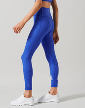 Woman wearing blue leggings with white accents on a gray background