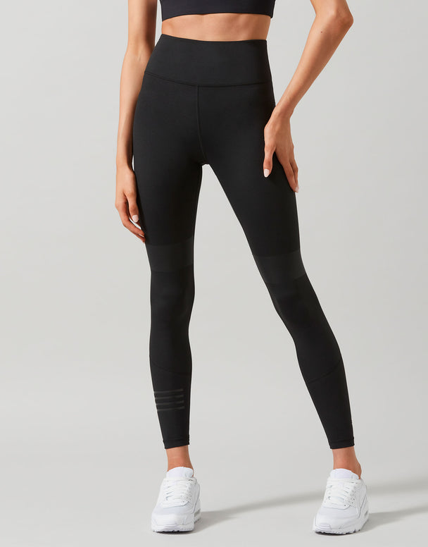 Person wearing black leggings and white sneakers on a gray background