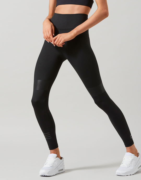 Person wearing black leggings and white sneakers on a light gray background