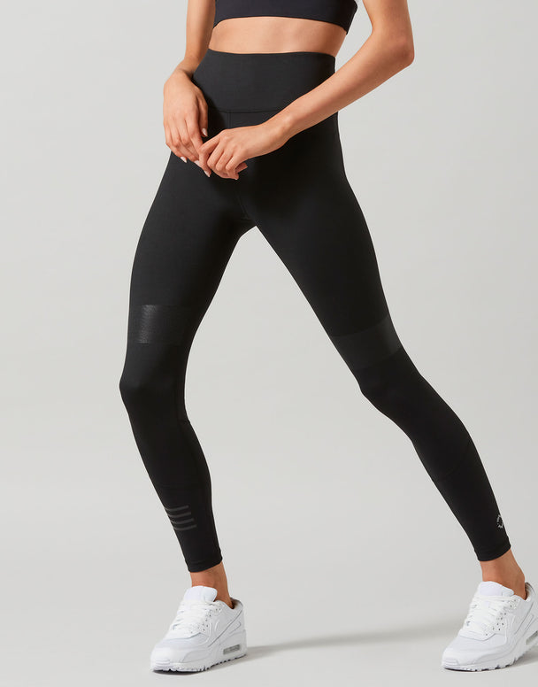 Person wearing black leggings and white sneakers on a light gray background