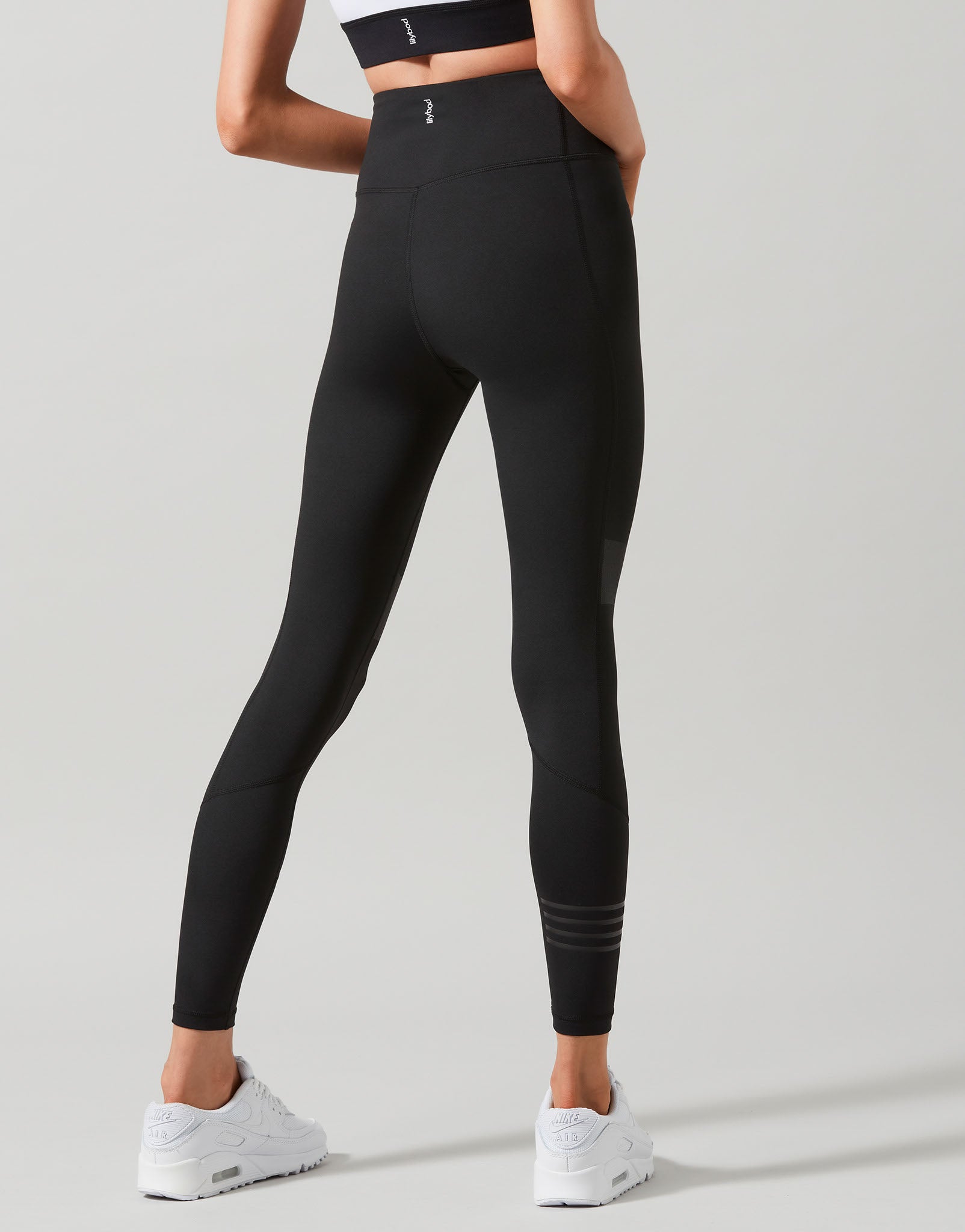 Person wearing black leggings on a light gray background