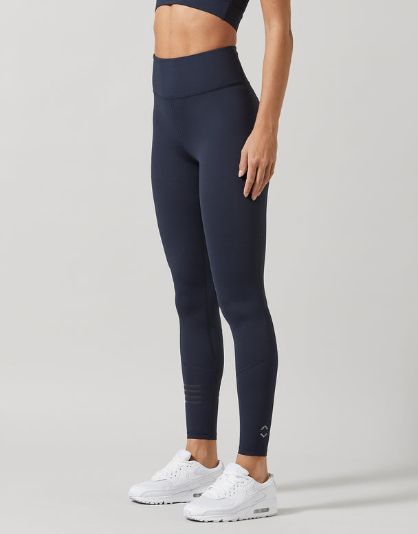 A woman wearing navy leggings on a light gray background