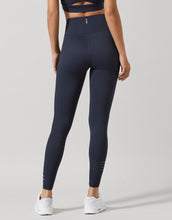 Person wearing navy Lilybod leggings on a light gray background