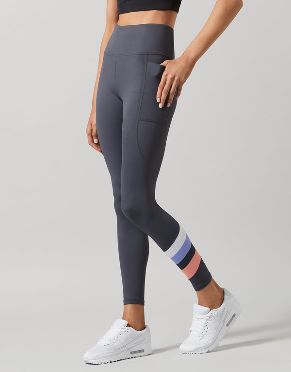 Person wearing dark gray leggings with a plain background