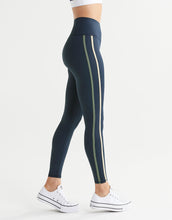 Dark blue leggings with green stripes worn by a person on a white background