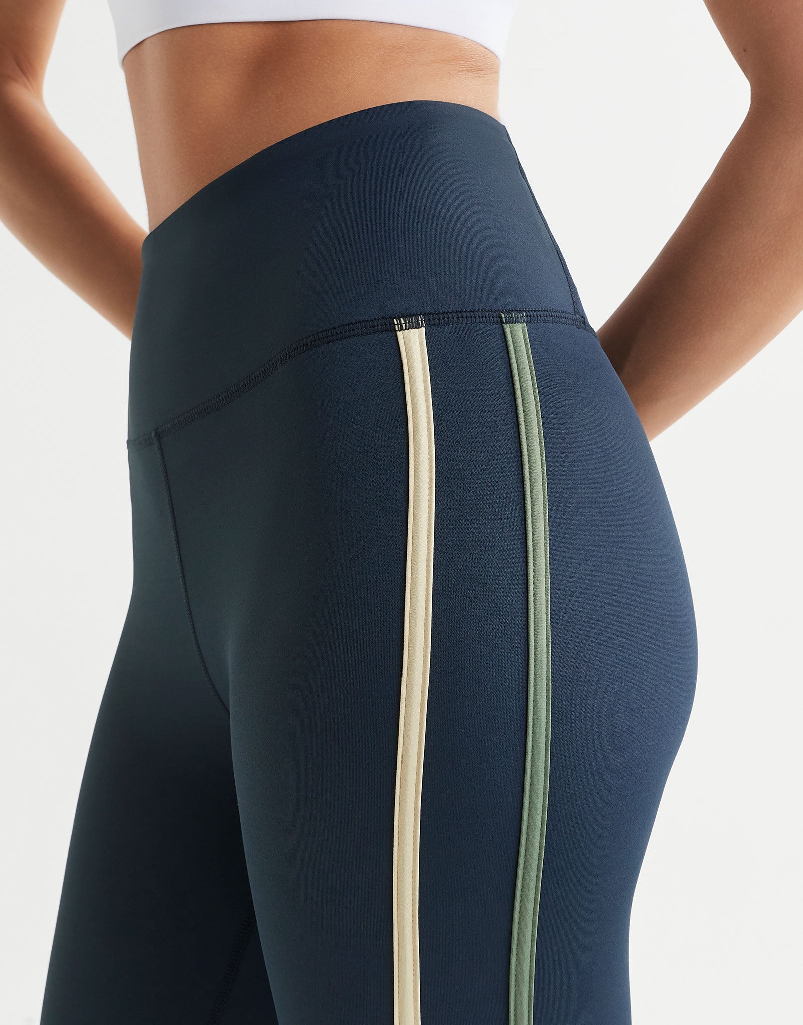 A woman wearing navy blue leggings  on a plain background.