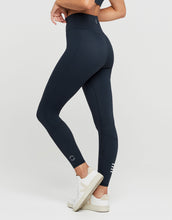 Woman wearing navy blue leggings with a logo on a white background