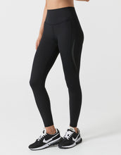 Person wearing black leggings and black sneakers on a white background