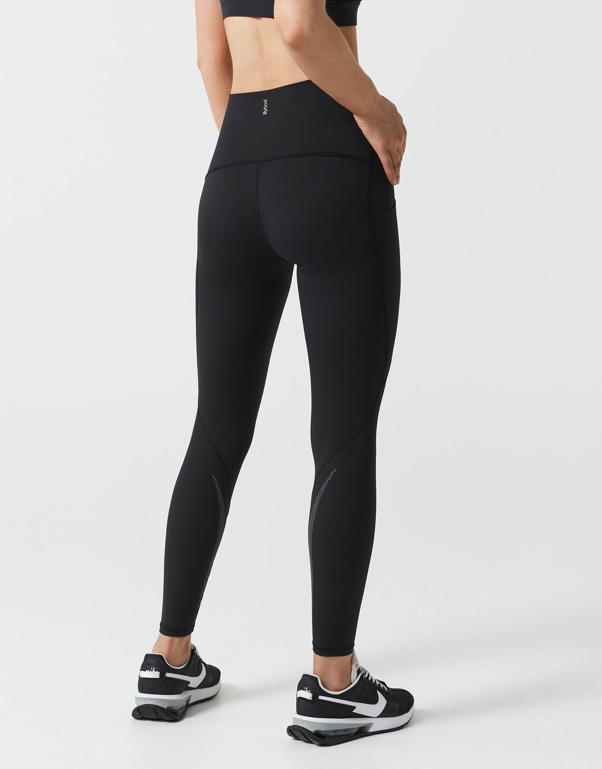 Person wearing black athletic leggings on a white background