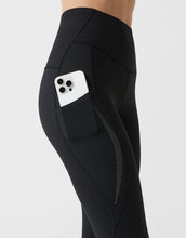 Black leggings with a pocket holding a smartphone on a light gray background