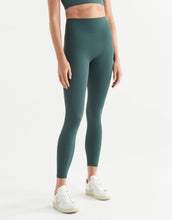 Person wearing teal leggings and white sneakers on a white background