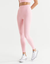 Side view of a woman wearing powder pink leggings and white sneakers