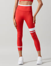 Red leggings with white stripes worn by a person on a gray background