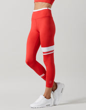 Red leggings with white stripes worn by a person on a gray background