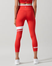 Red leggings with white stripes worn by a person on a light gray background