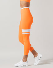 Orange leggings with white stripes worn by a person on a light gray background
