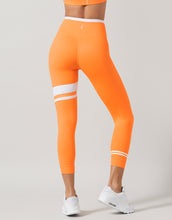 Orange leggings with white stripes worn by a person on a light gray background