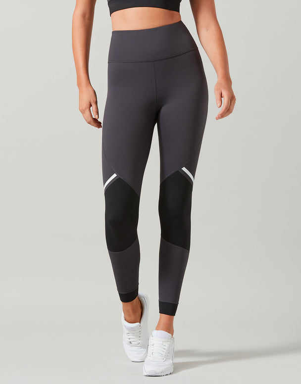 Person wearing black leggings with white accents on a gray background