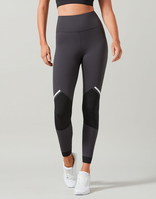 Person wearing black leggings with white accents on a gray background