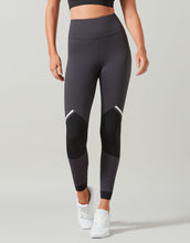 Person wearing black leggings with white accents on a gray background