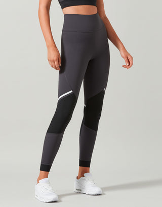 Person wearing black leggings with a subtle design on a light gray background