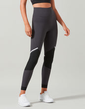 Person wearing black leggings with a subtle design on a light gray background