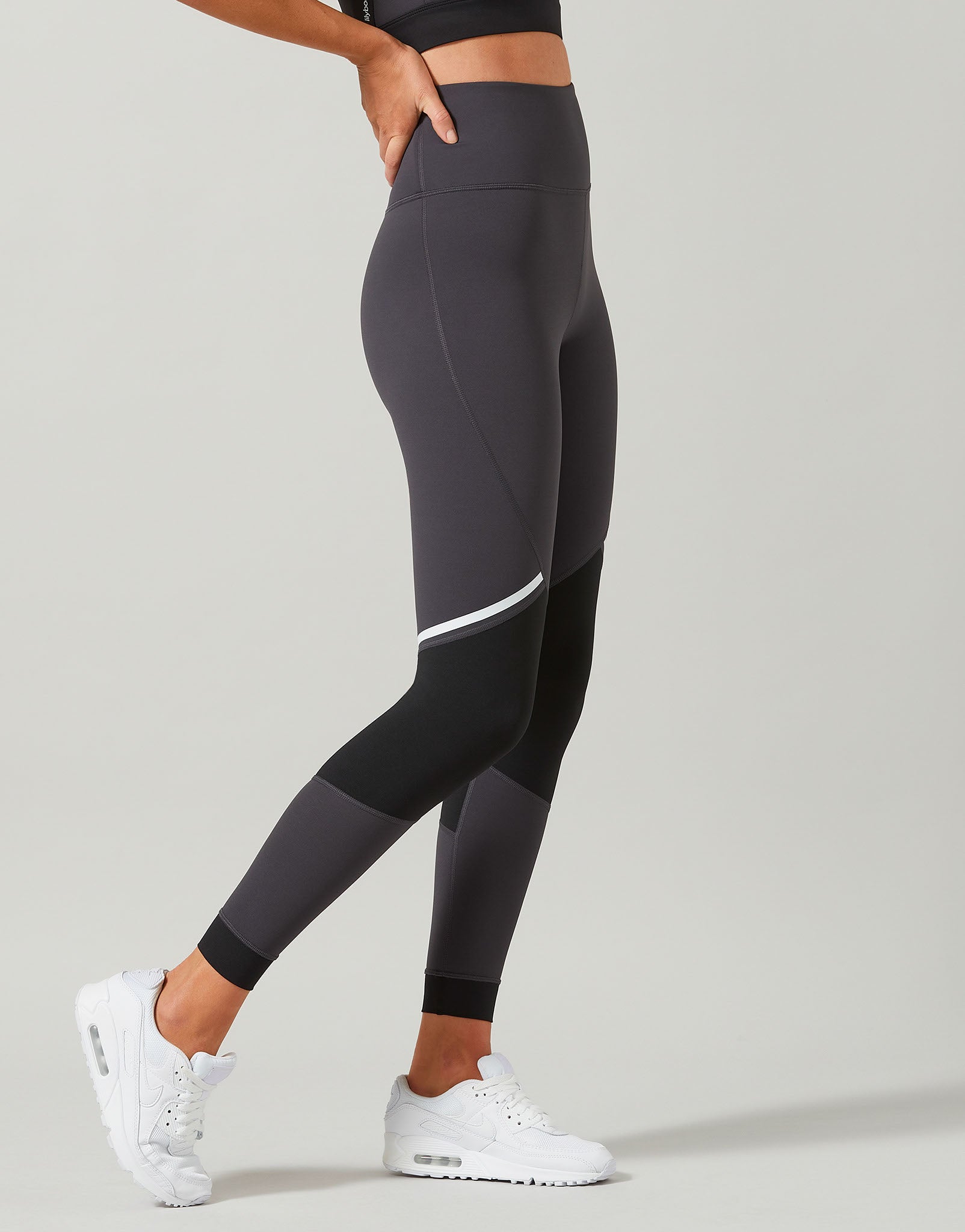 Person wearing black leggings with a white stripe on a light gray background