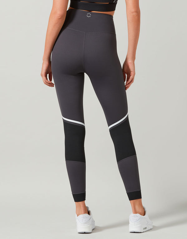 Person wearing gray leggings with white accents on a plain background