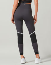 Person wearing gray leggings with white accents on a plain background