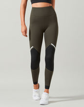 Person wearing olive green and black leggings on a gray background