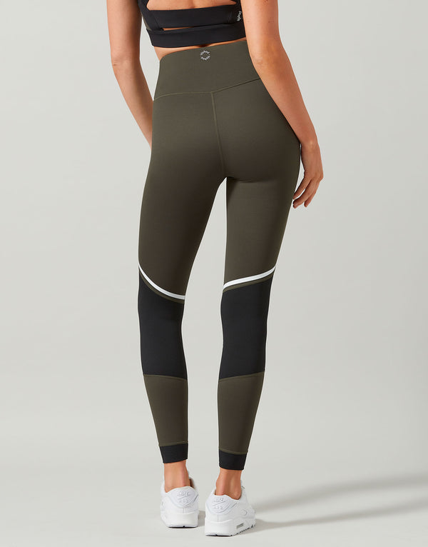 Person wearing olive green and black leggings on a gray background