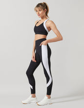 Woman wearing a black and white athletic outfit on a light gray background