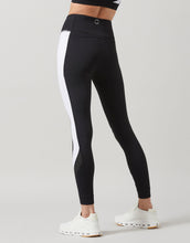 Black leggings with white side stripe worn by a person on a light gray background